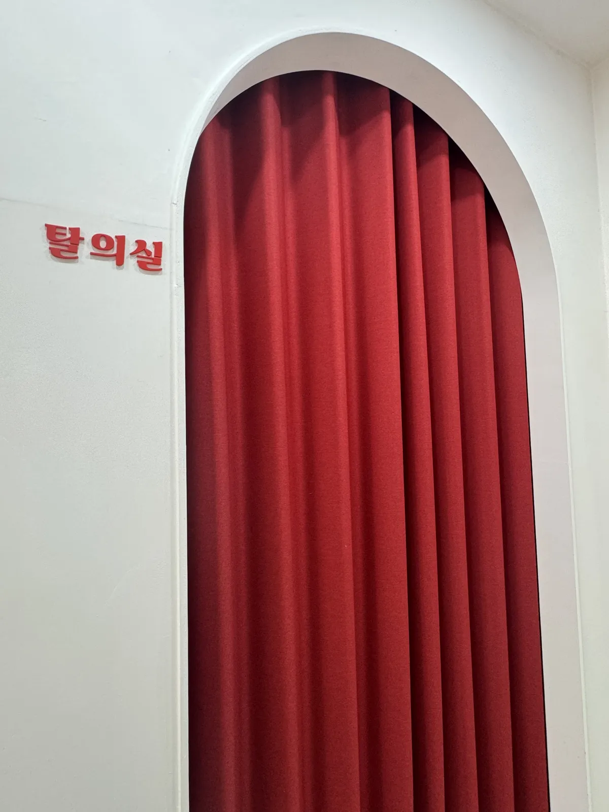 빨간 커튼이 드리운 아치형 탈의실 입구